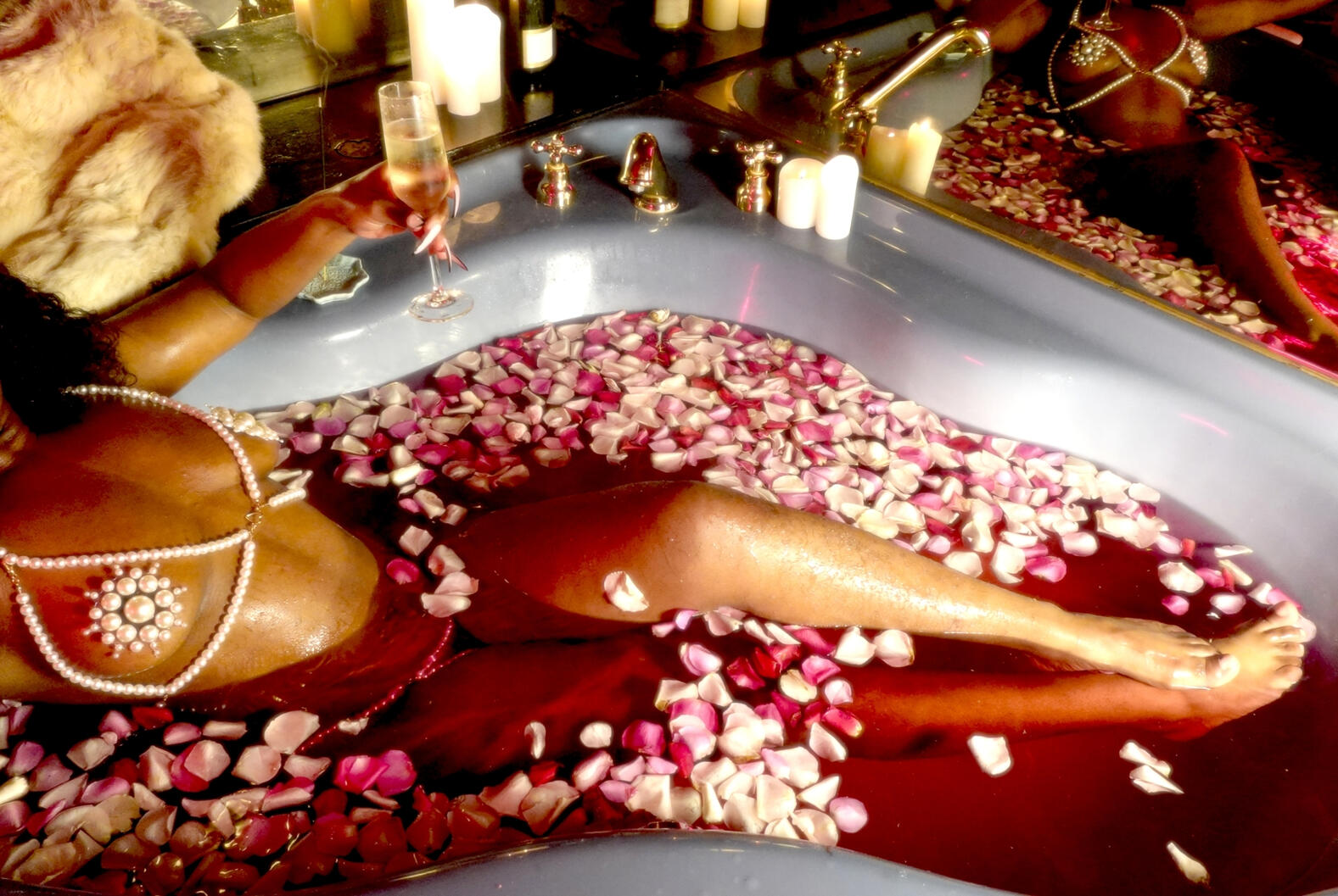 Black woman in pearl lingerie bathes in a hot tub filled with rose petals